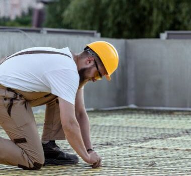 A man working on a commercial roof replacement in Cooper City, FL.