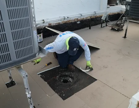 An employee of a commercial roofing company doing commercial roof penetration repair in Deerfield Beach