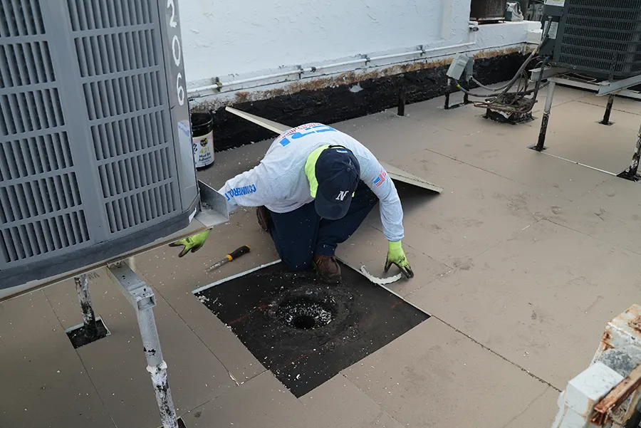 An employee of a commercial roofing company doing commercial roof penetration repair in Deerfield Beach